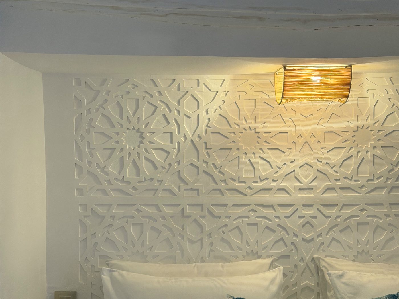 Tête de lit en plâtre ciselé éclairée par une applique tressée